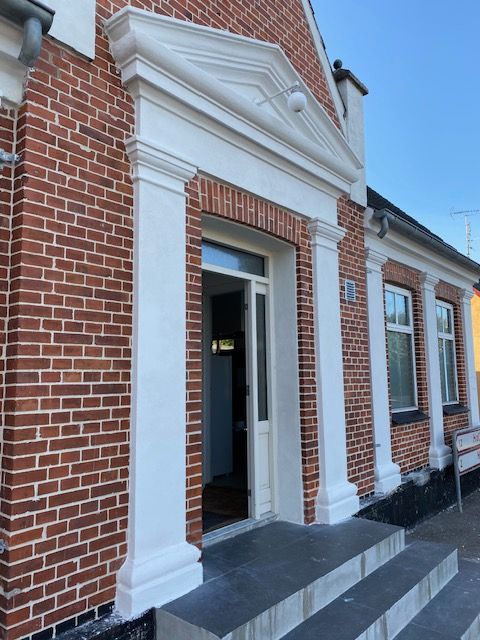 En murstensbygning med hvid dør og trin