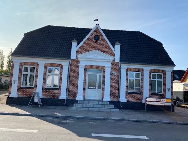 En stor murstensbygning med sort tag og hvide lister