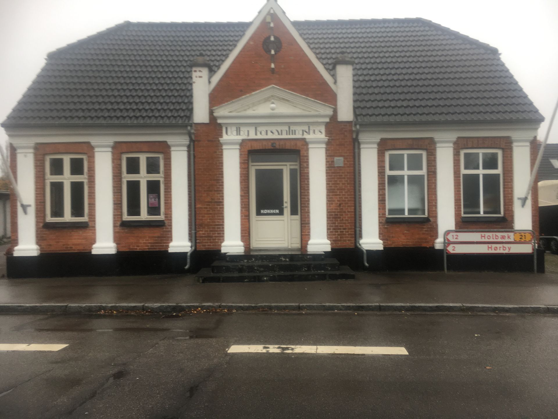 En murstensbygning med sort tag og hvide lister