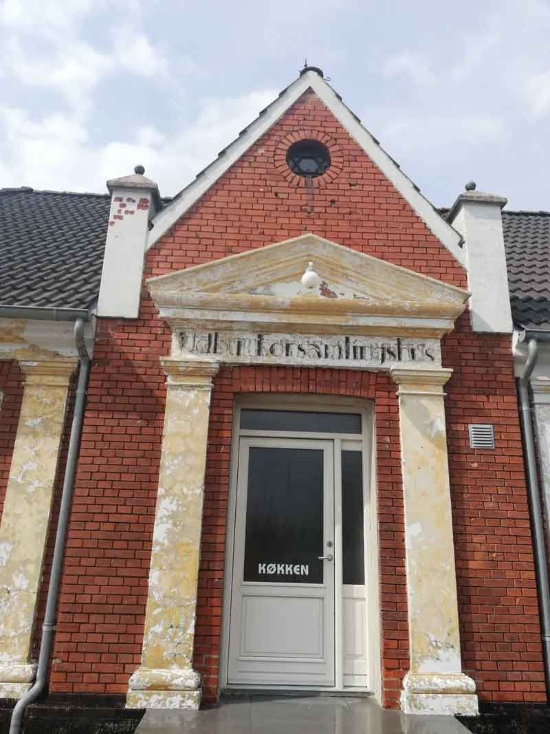 En rød murstensbygning med hvid dør og søjler