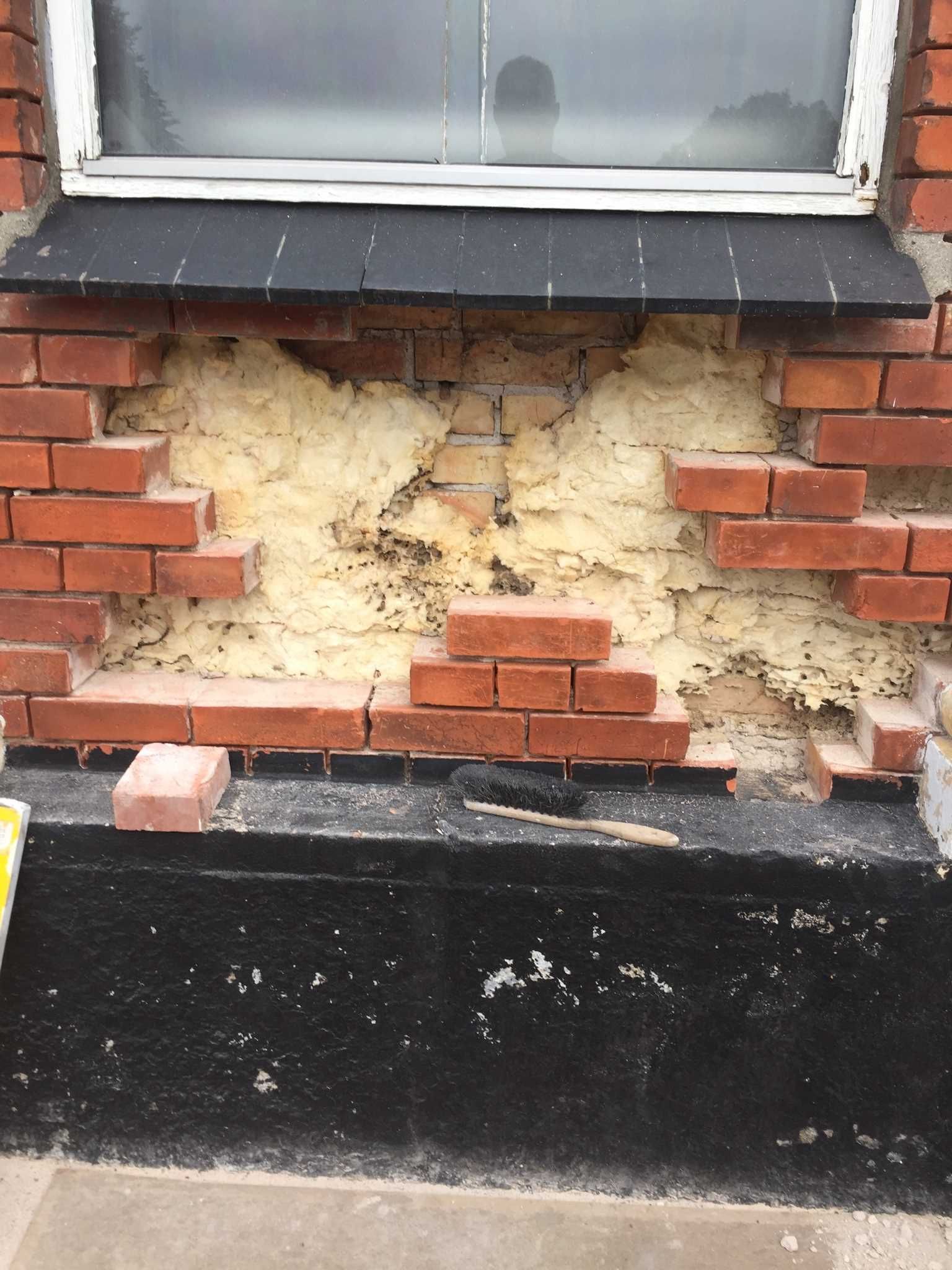 En murstensvæg med et hul i og et vindue.