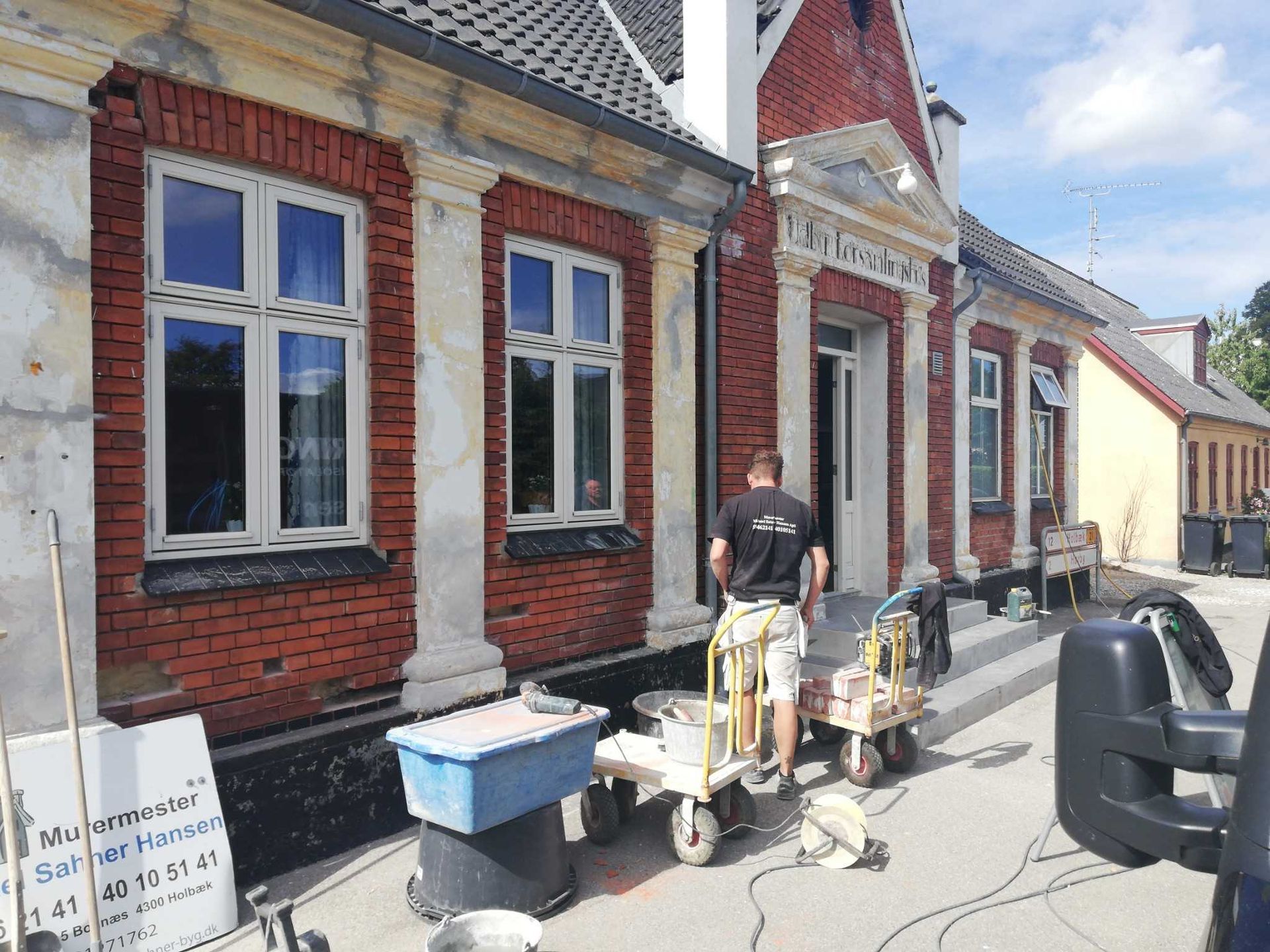 En mand står foran en murstensbygning.