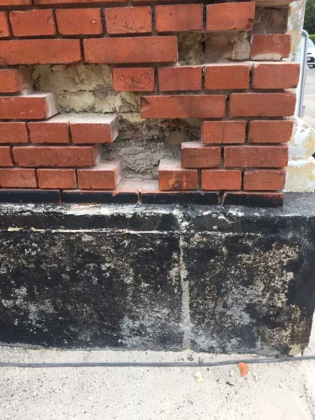 Et nærbillede af en murstensvæg med et hul i