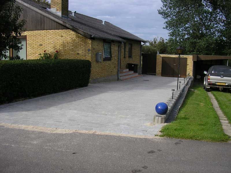 En bil er parkeret foran et murstenshus