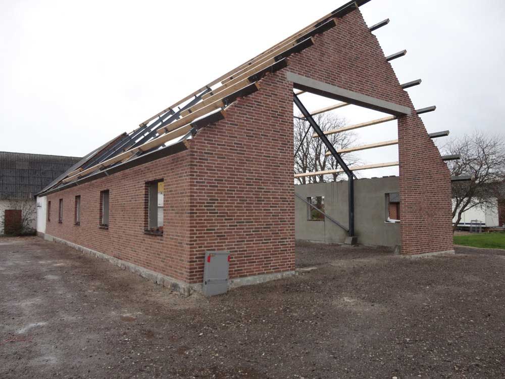 En murstensbygning med tag, der bygges