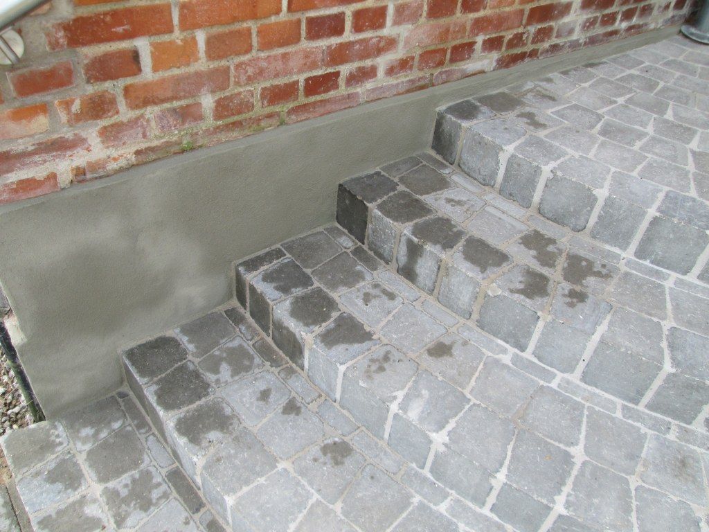 Et sæt stentrapper, der fører op til en murstensvæg.