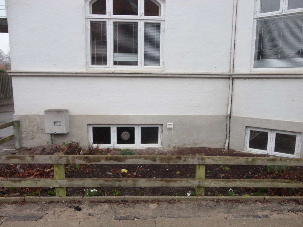 En hvid bygning med et plankeværk foran