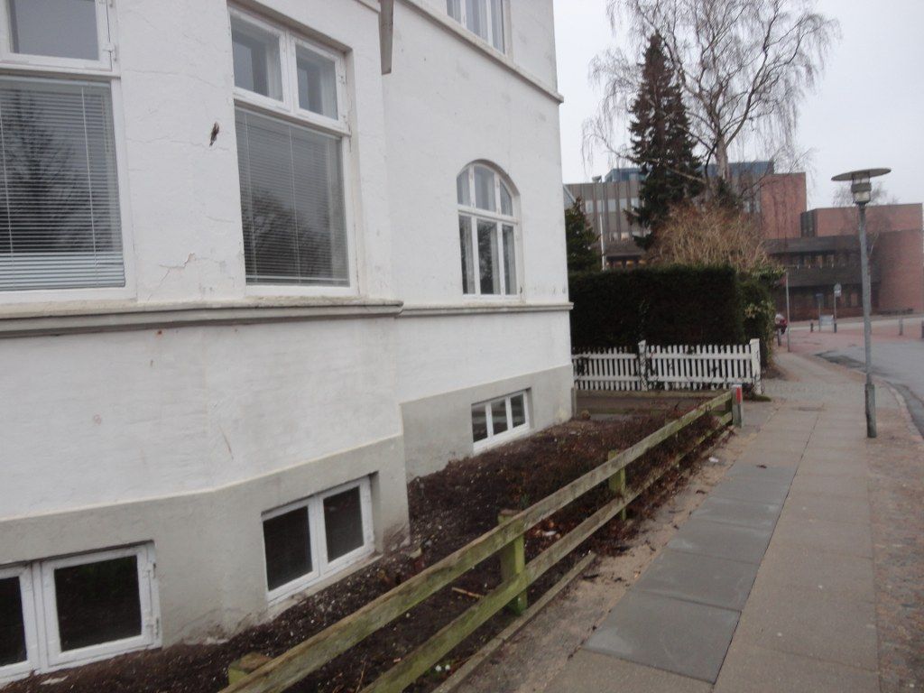 En hvid bygning med et plankeværk foran