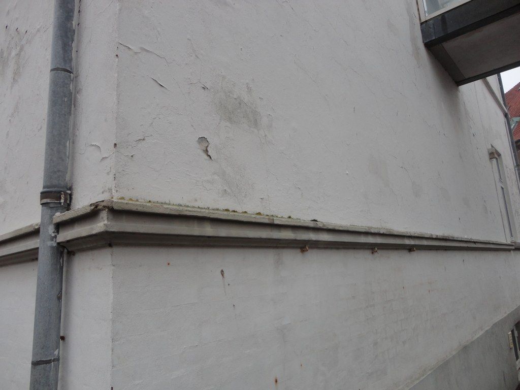 En hvid bygning med en tagrende på siden af ​​.