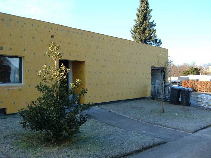 Et gult hus med et lille træ foran.