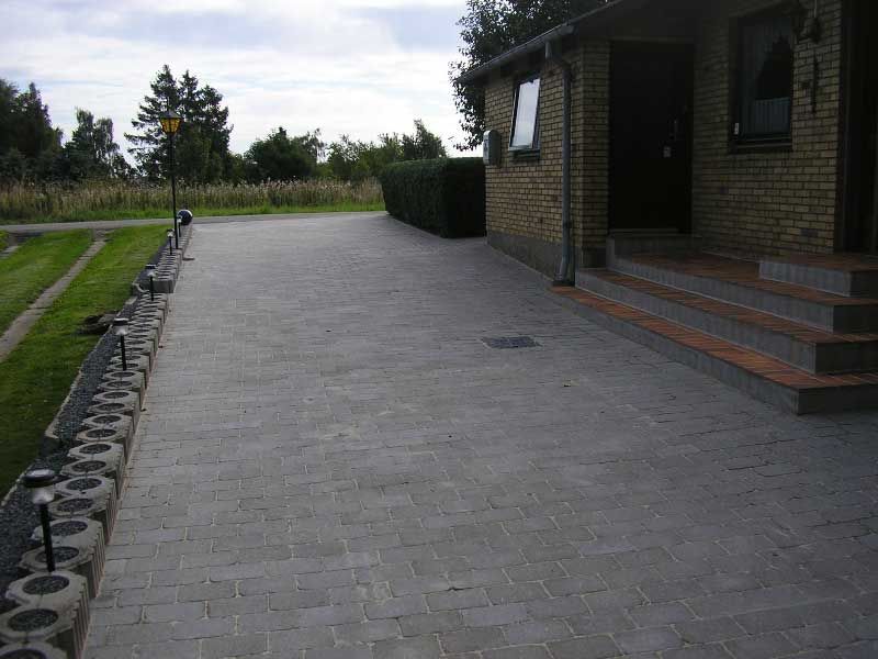 En muret indkørsel, der fører til et murstenshus