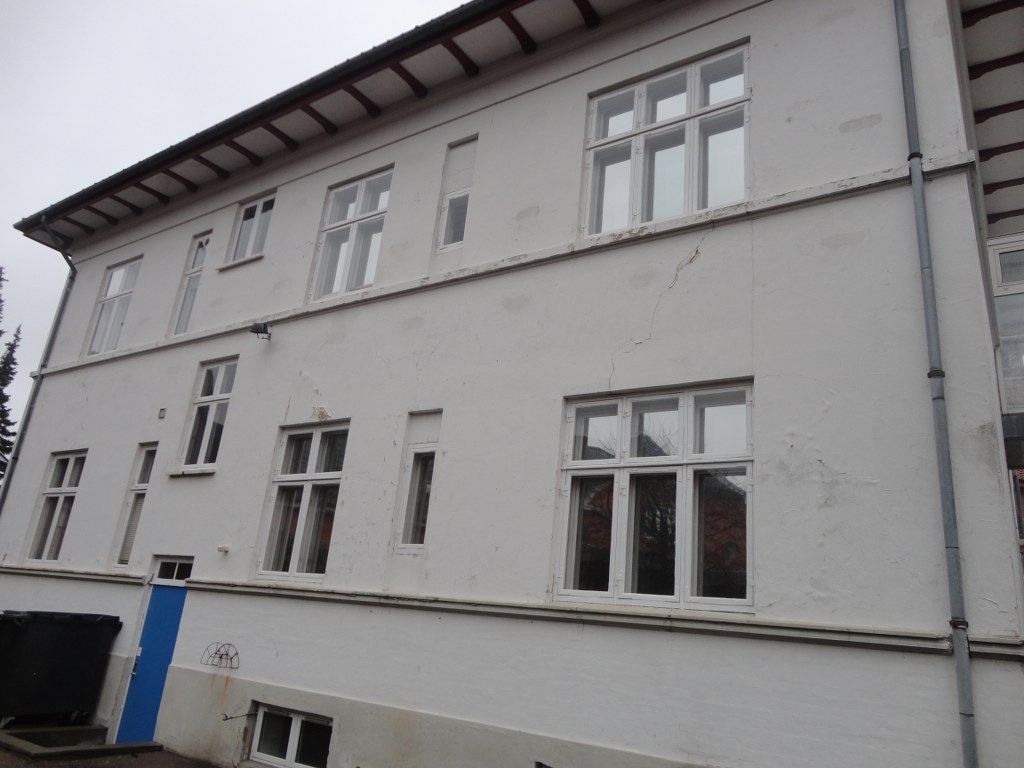 En stor hvid bygning med mange vinduer og en blå dør