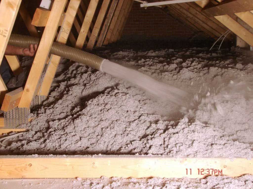 En slange bliver brugt til at blæse isolering ind i et loft