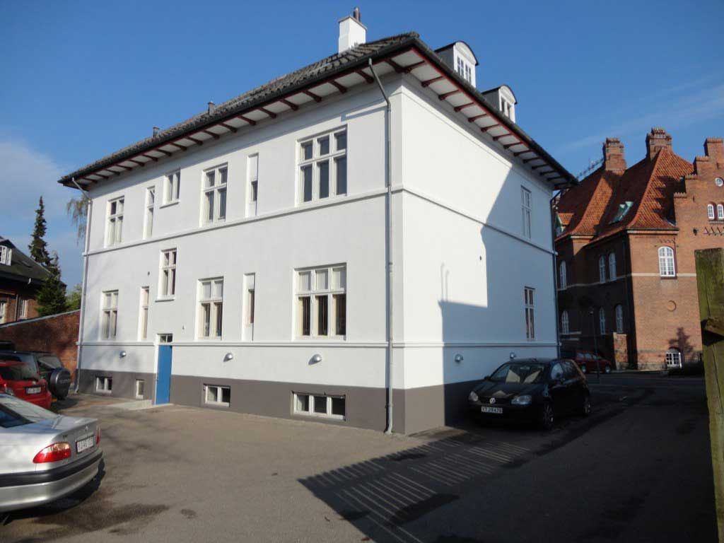 En hvid bygning med biler parkeret foran den