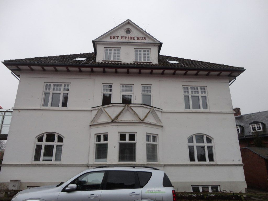 En stor hvid bygning med en bil parkeret foran