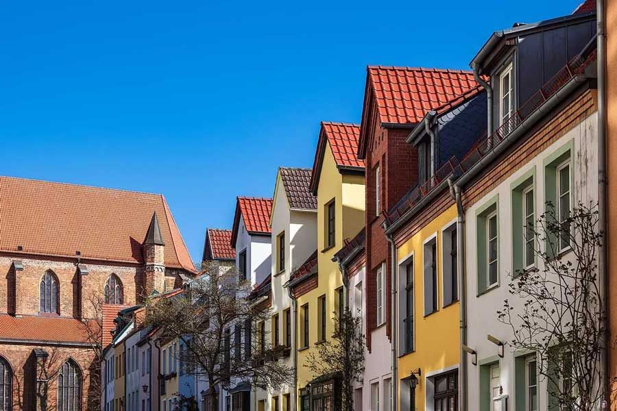En række farverige bygninger med røde tegltage i en by.