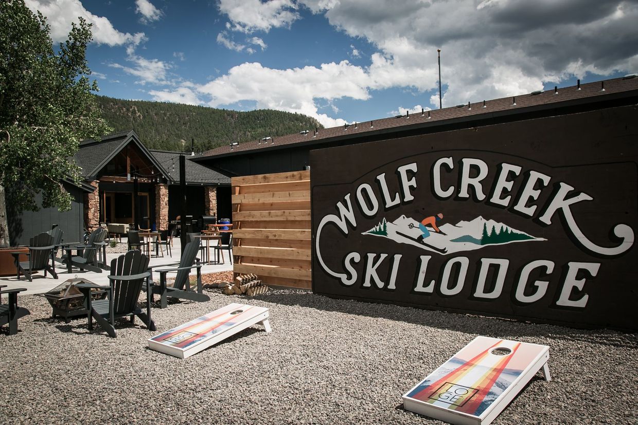 Wolf Creek Ski Lodge sign on a rustic lodge with outdoor seating in a mountain setting