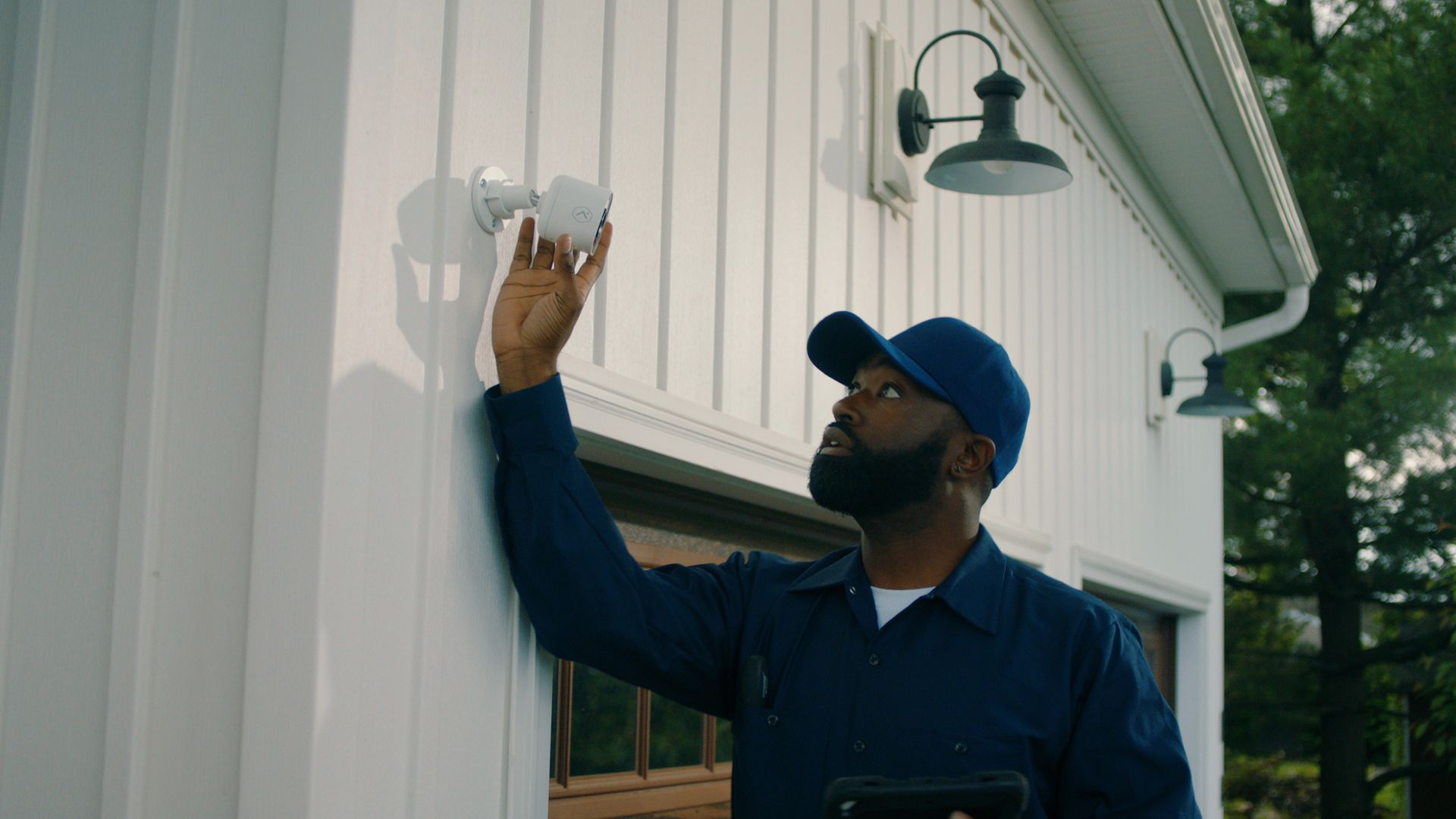 A man is working on the roof of a house next to a truck that says ' roofing ' on it