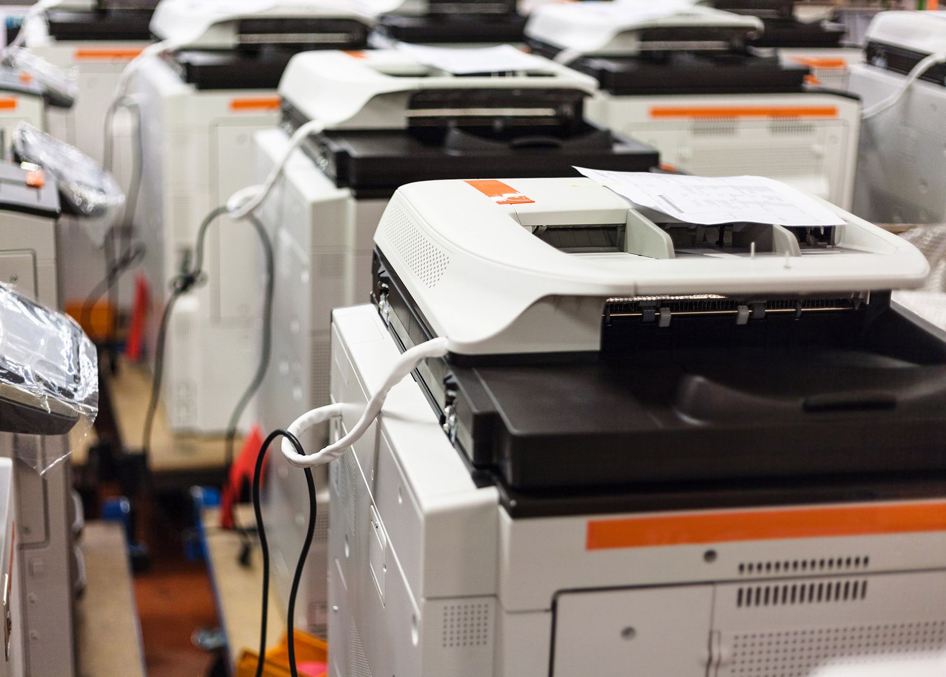 Row of white and black office printers. Orange accents. Row of white and black office printers. Orange accents.