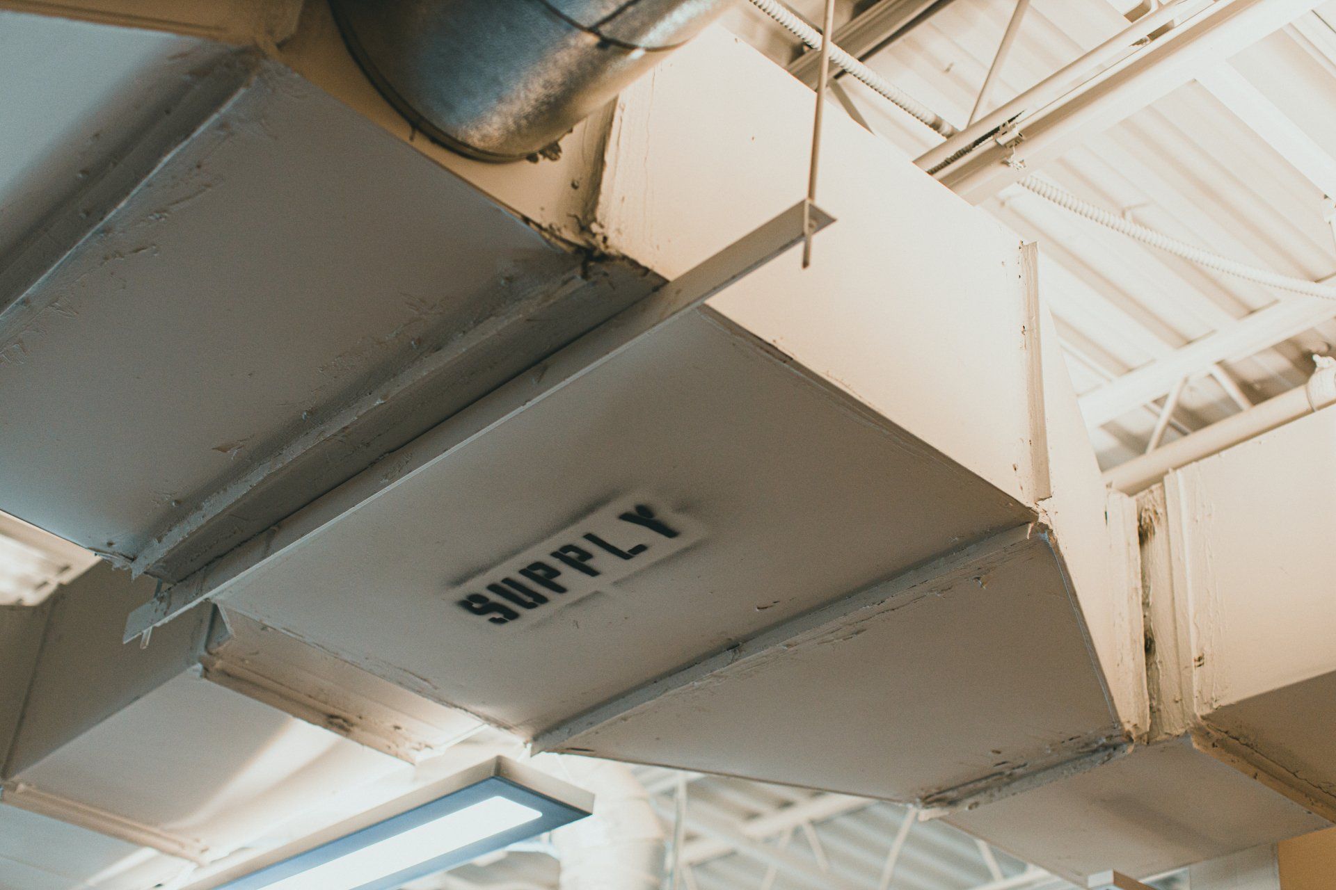 A supply duct is hanging from the ceiling of a building.