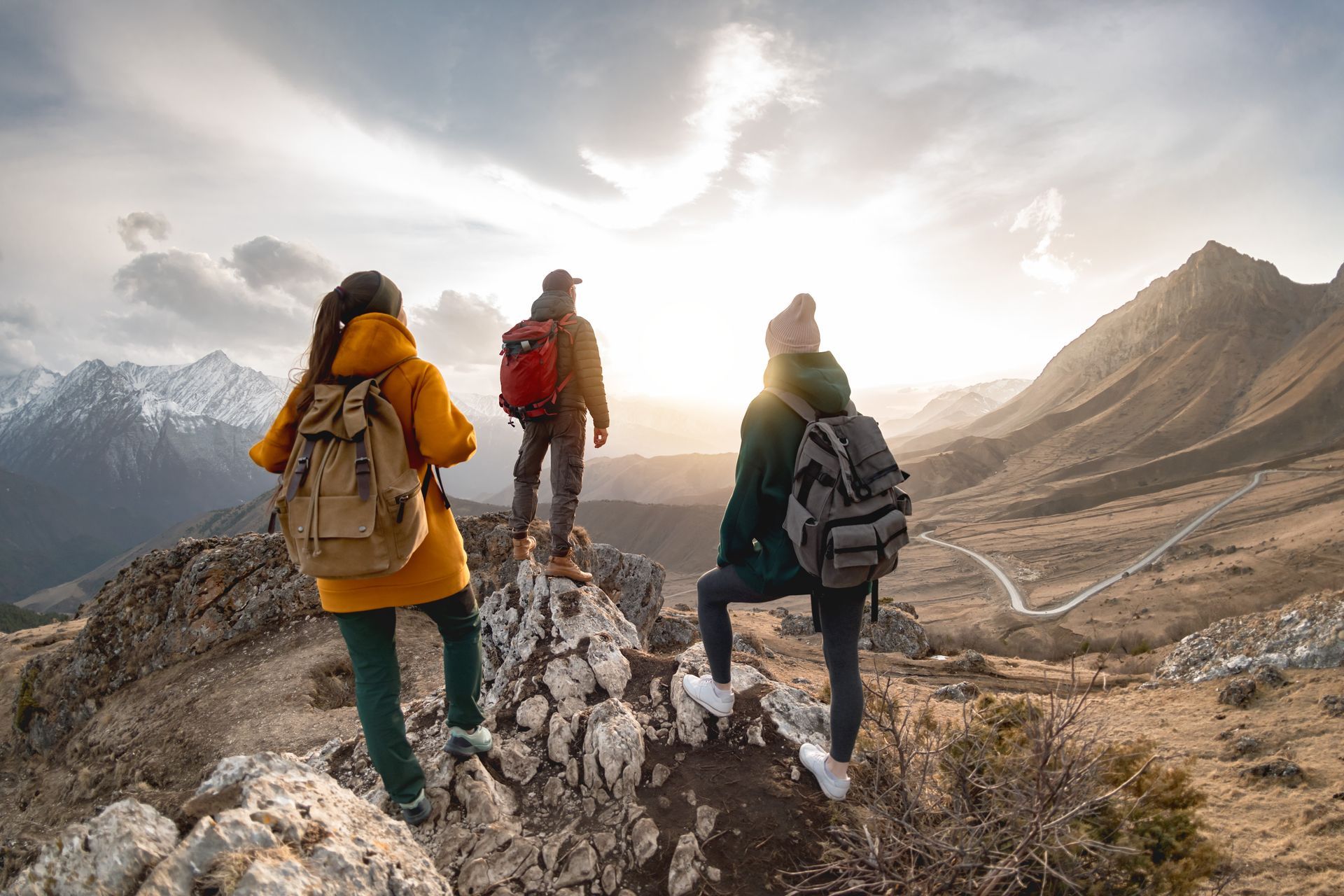 three people with backpacks are standing on top of a mountain .