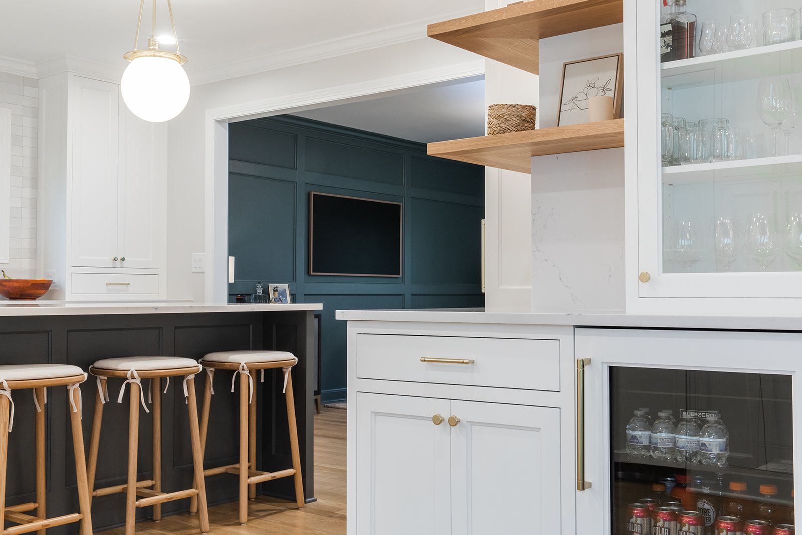 A kitchen with a bar and stools and a refrigerator