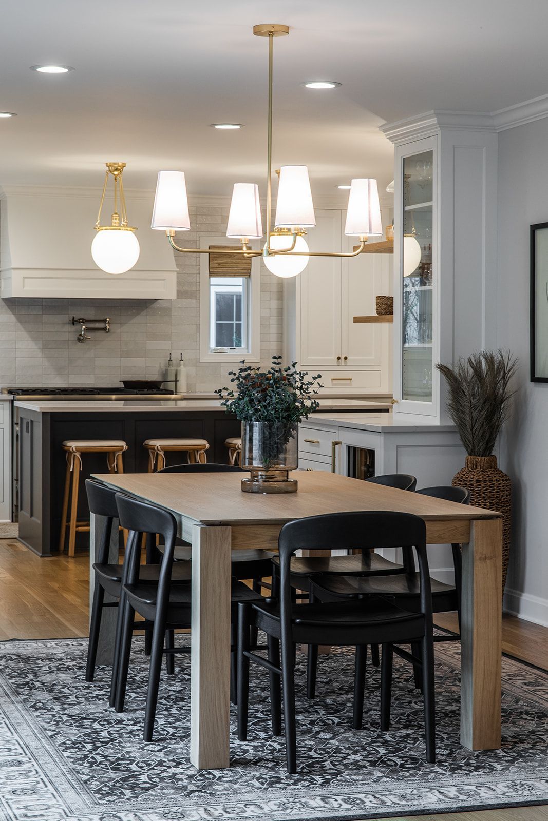 A dining room table and chairs in a kitchen with a chandelier hanging from the ceiling