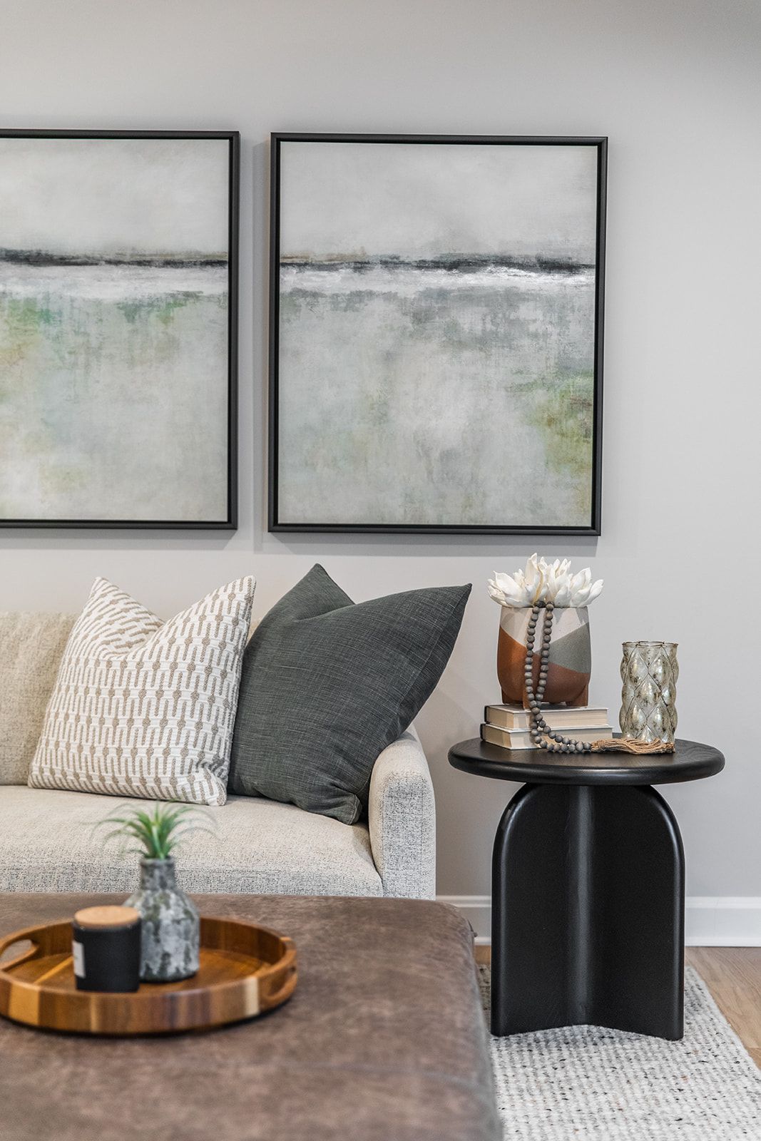 A living room with a couch , table , and two paintings on the wall