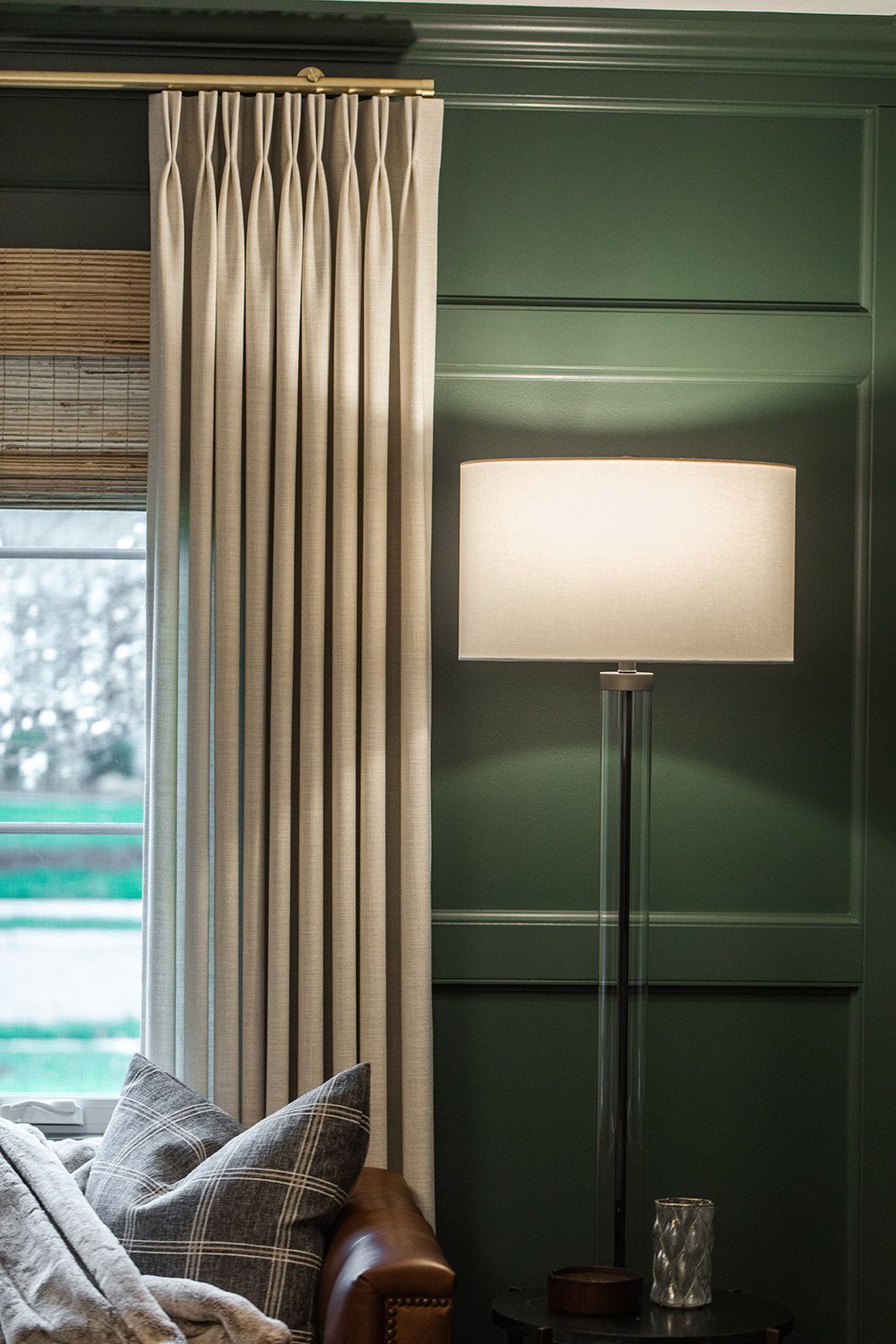 A living room with a couch , lamp , and green wall