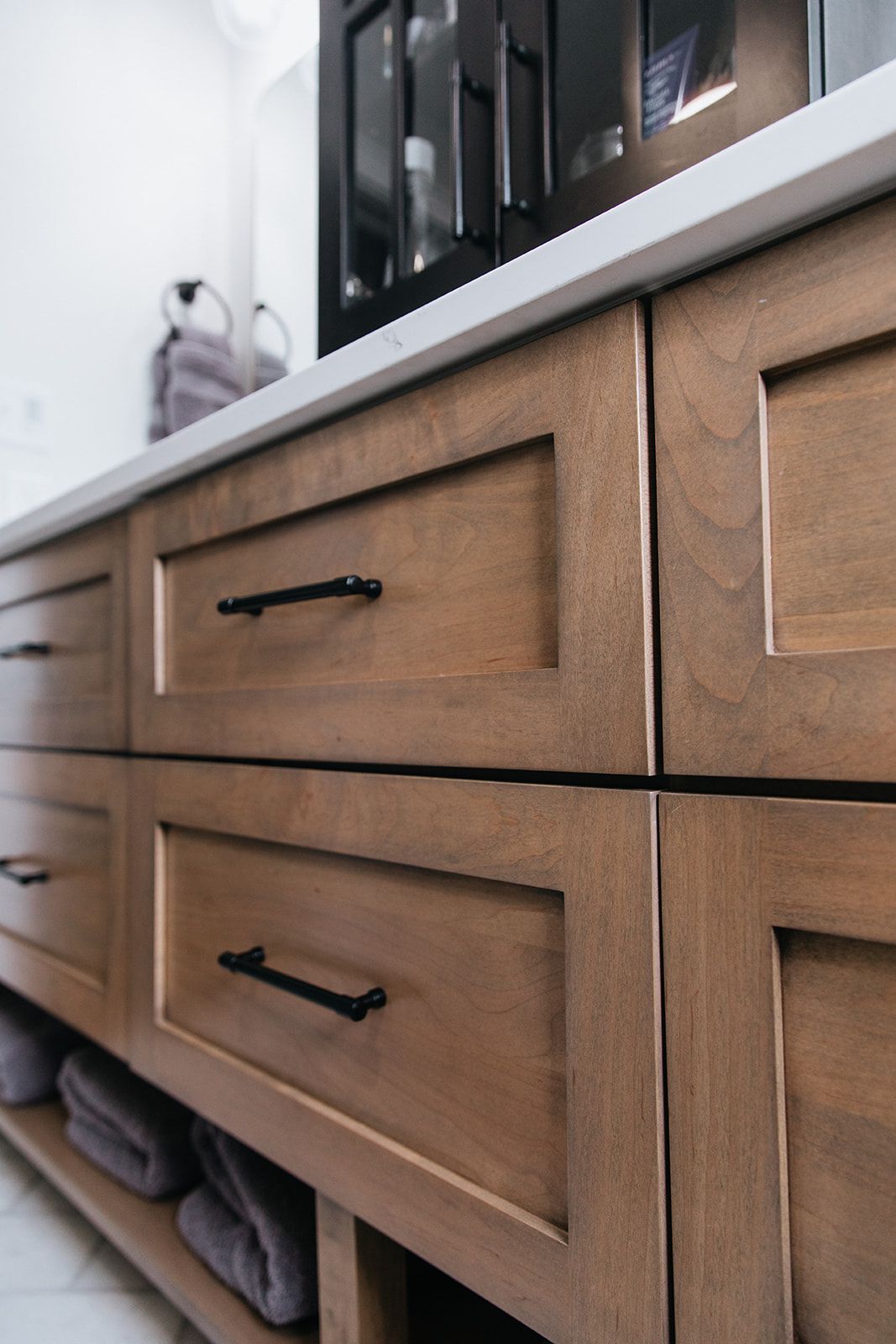 A bathroom vanity with wooden drawers and black handles