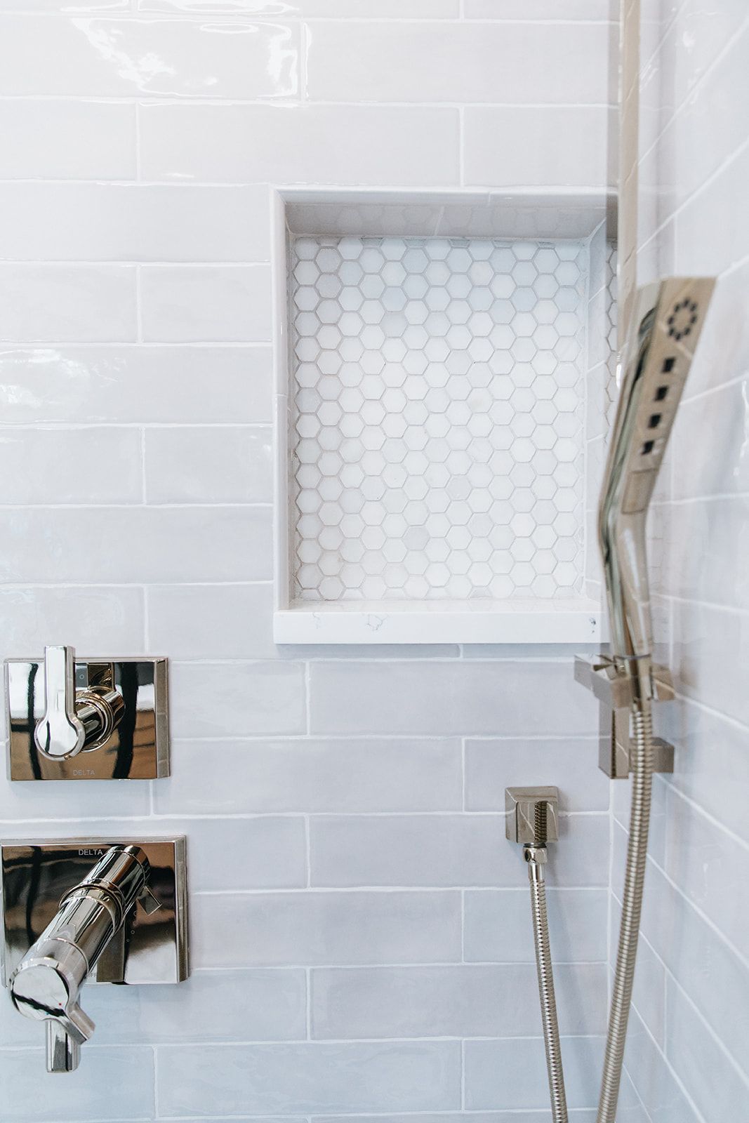 A close up of a shower head in a bathroom with white tiles