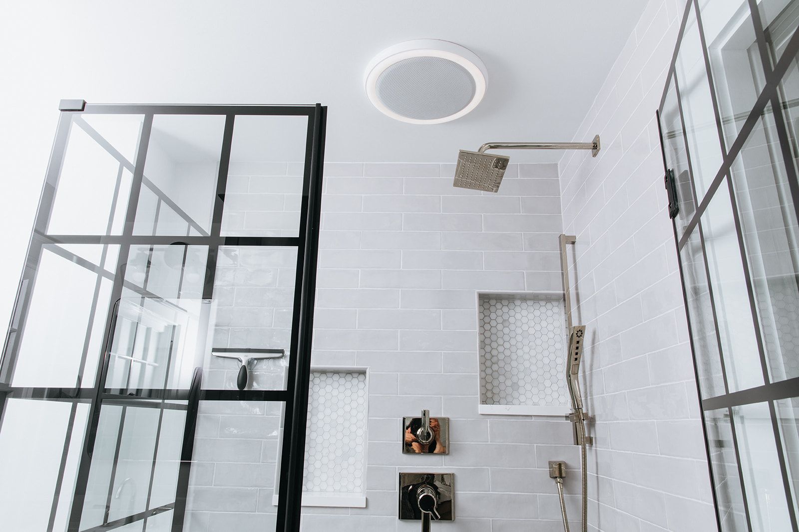 A bathroom with a walk in shower and a speaker on the ceiling