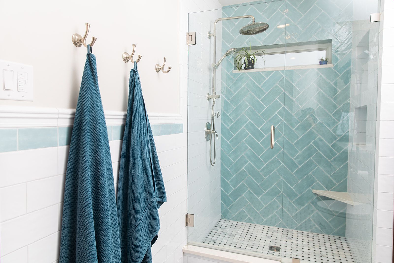 A bathroom with blue tiles and a walk in shower with a glass door