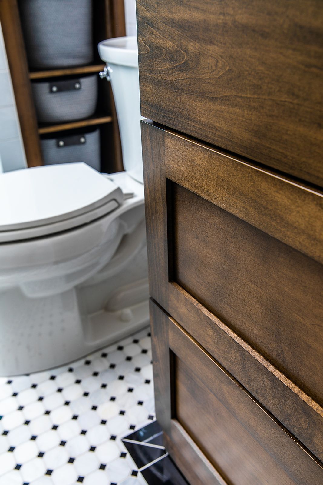 A bathroom with a toilet and a wooden cabinet