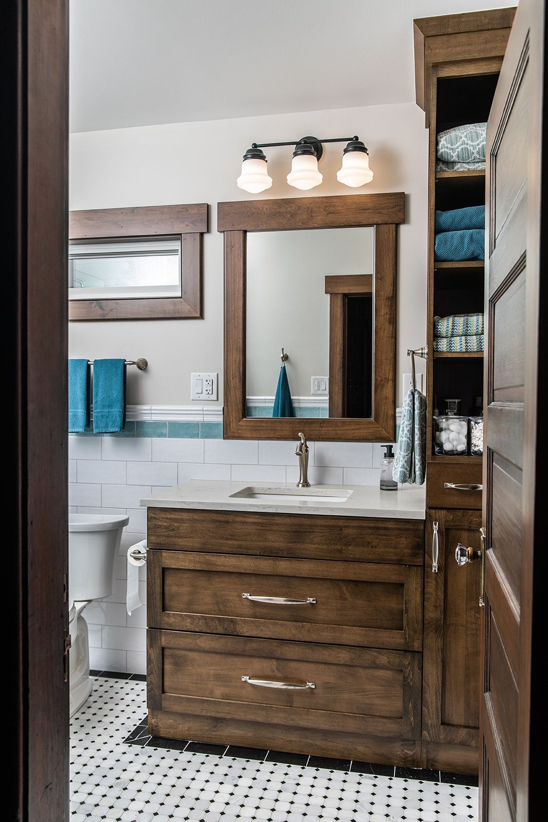 A bathroom with a wooden vanity , mirror and toilet
