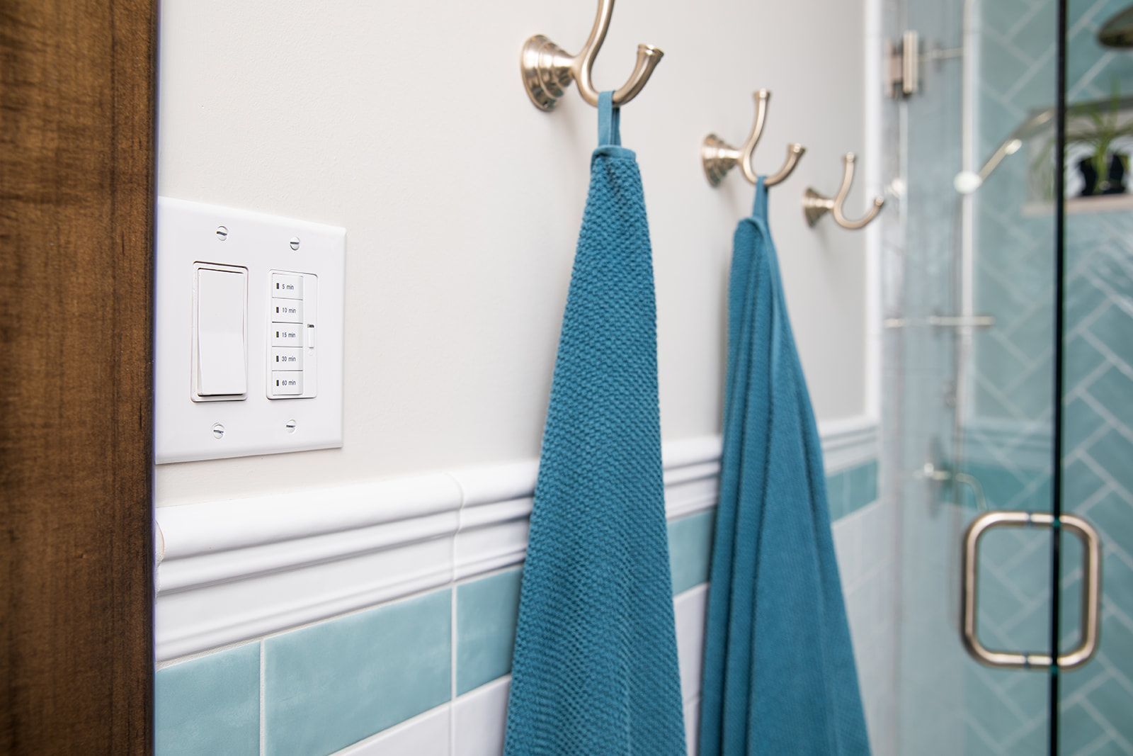 Two blue towels are hanging on hooks in a bathroom