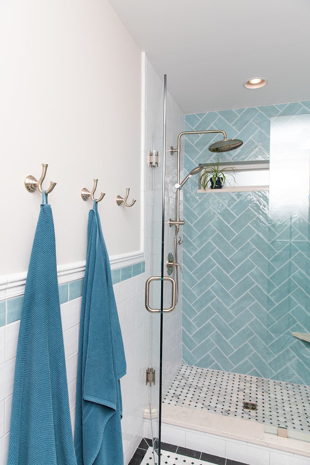 A bathroom with blue towels hanging on hooks and a walk in shower