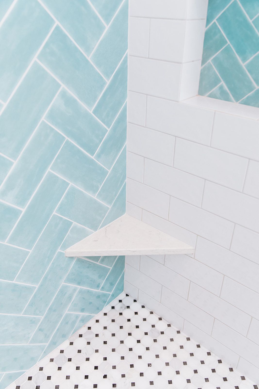 A shower with blue and white tiles and a corner shelf