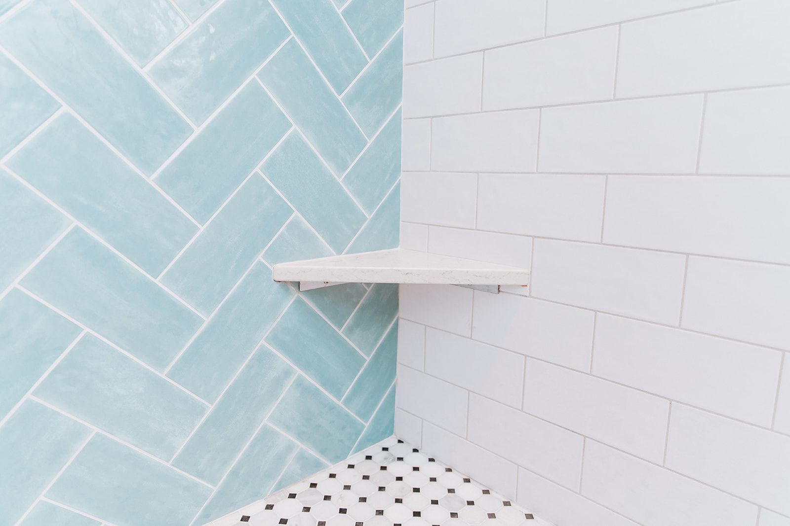 A shower with blue and white tiles and a shelf in the corner