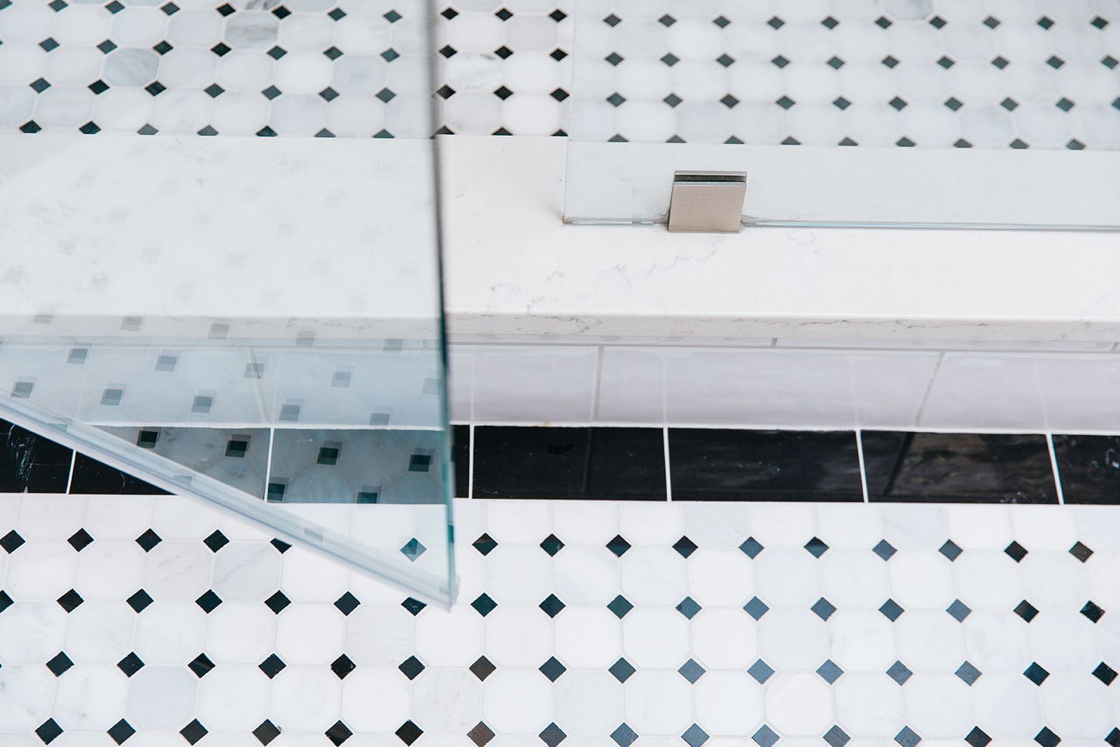 A bathroom with black and white tiles and a glass shower door