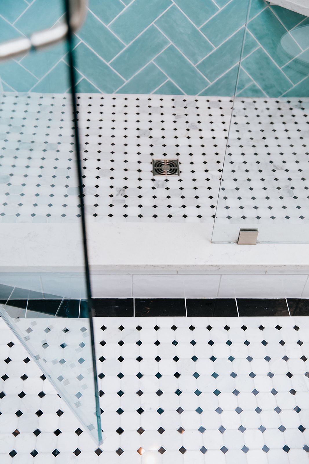 A shower stall with a glass door and a black and white tile floor