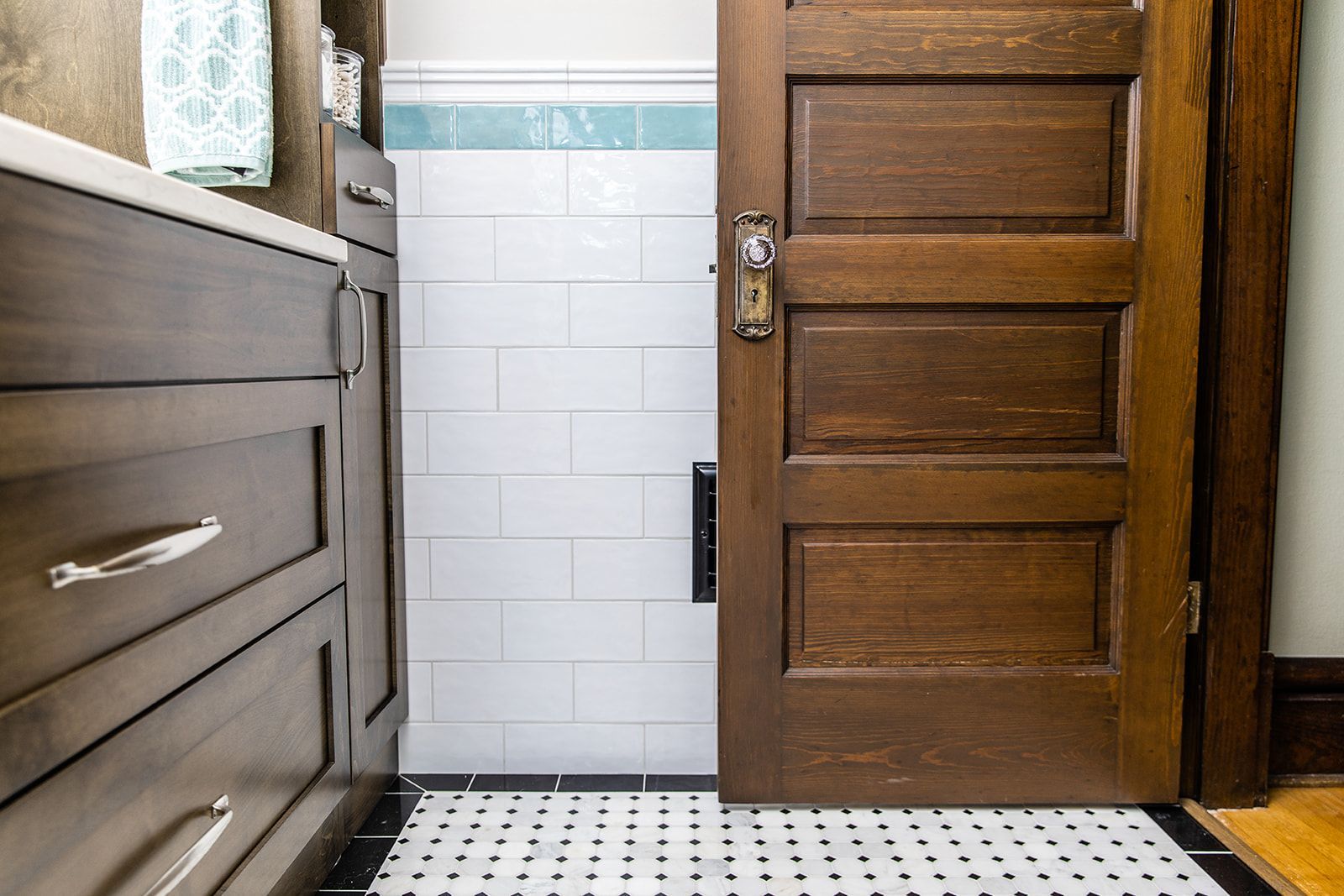 A bathroom with a wooden door and white tiles