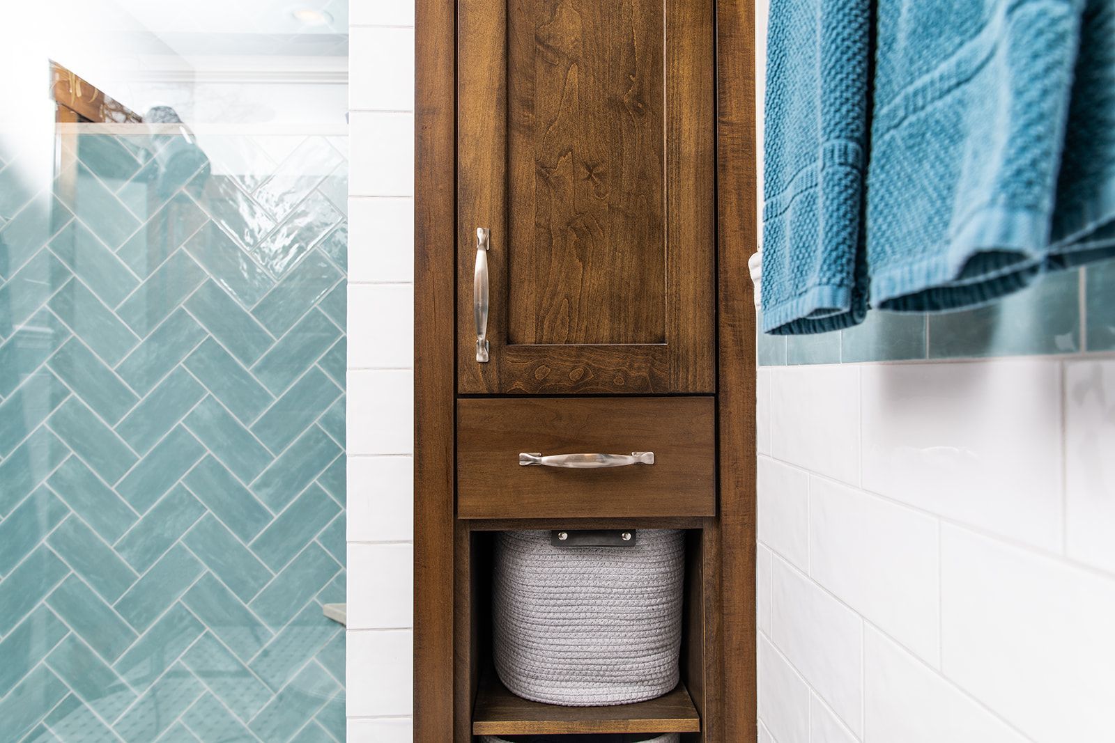 A bathroom with a wooden cabinet and towels hanging on the wall