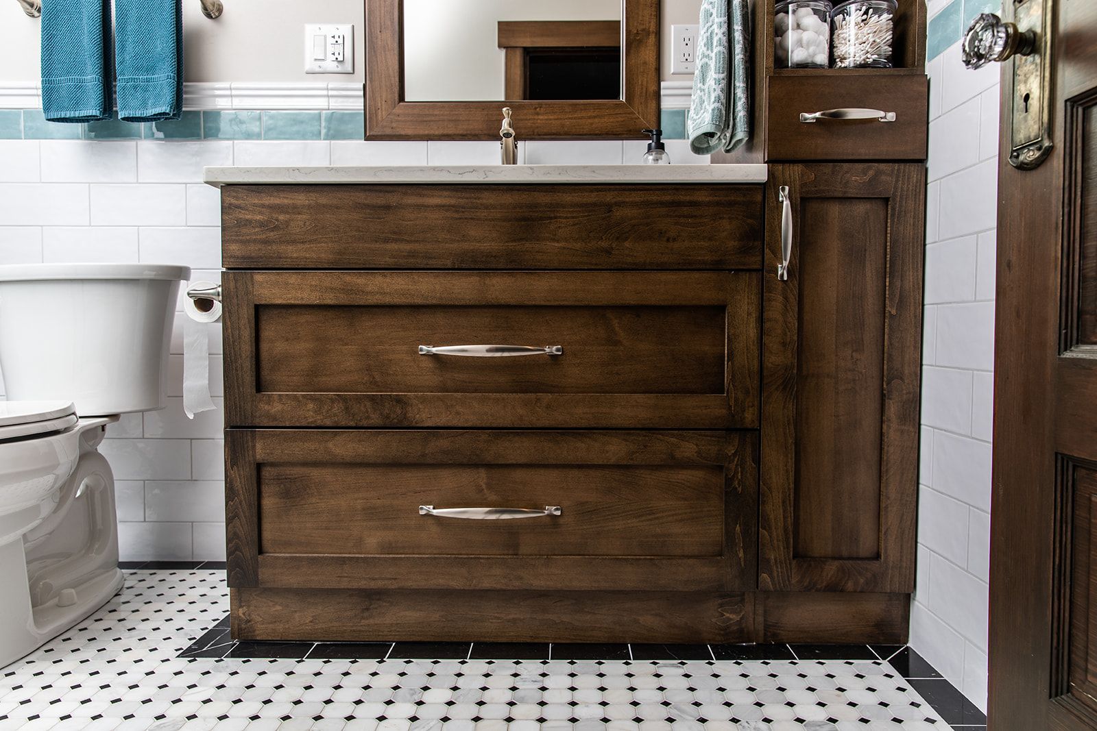 A bathroom with a wooden cabinet and towels hanging on the wall