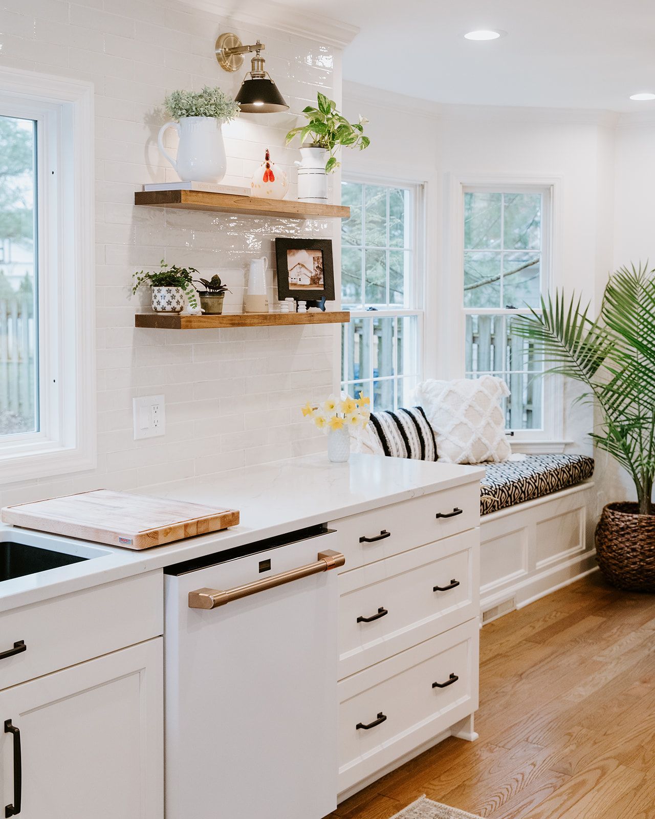 A kitchen with white cabinets and a window seat