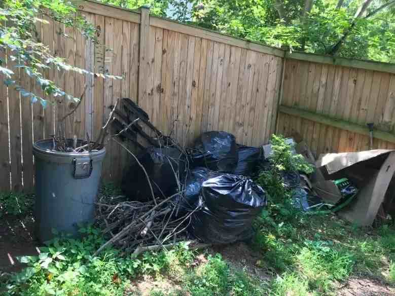 a pile of trash is sitting next to a wooden fence