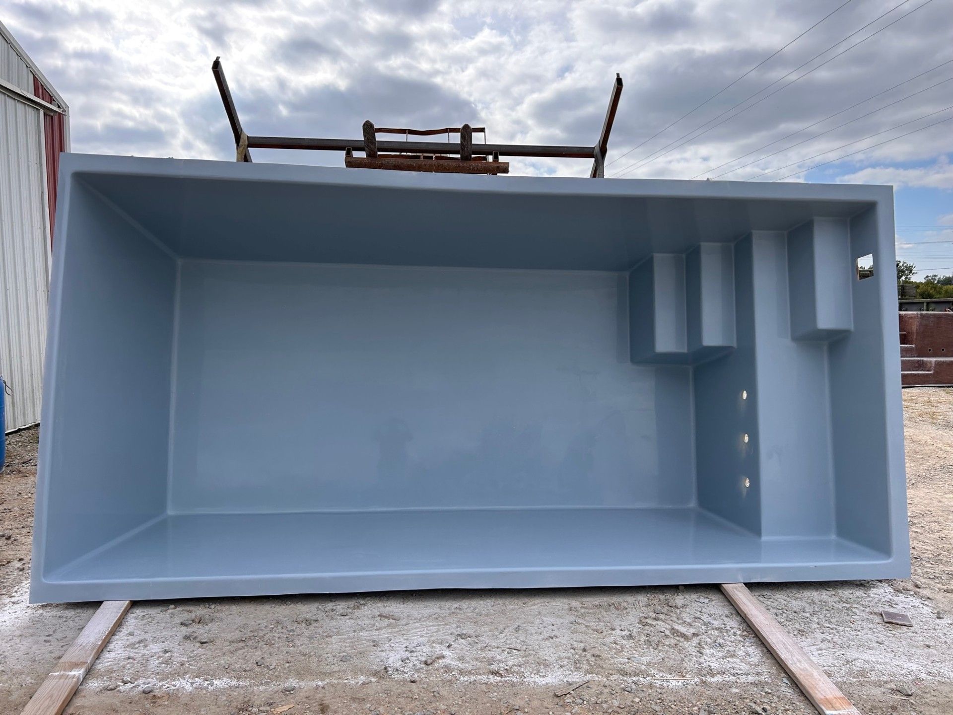 A large gray container is sitting on the ground in front of a building.