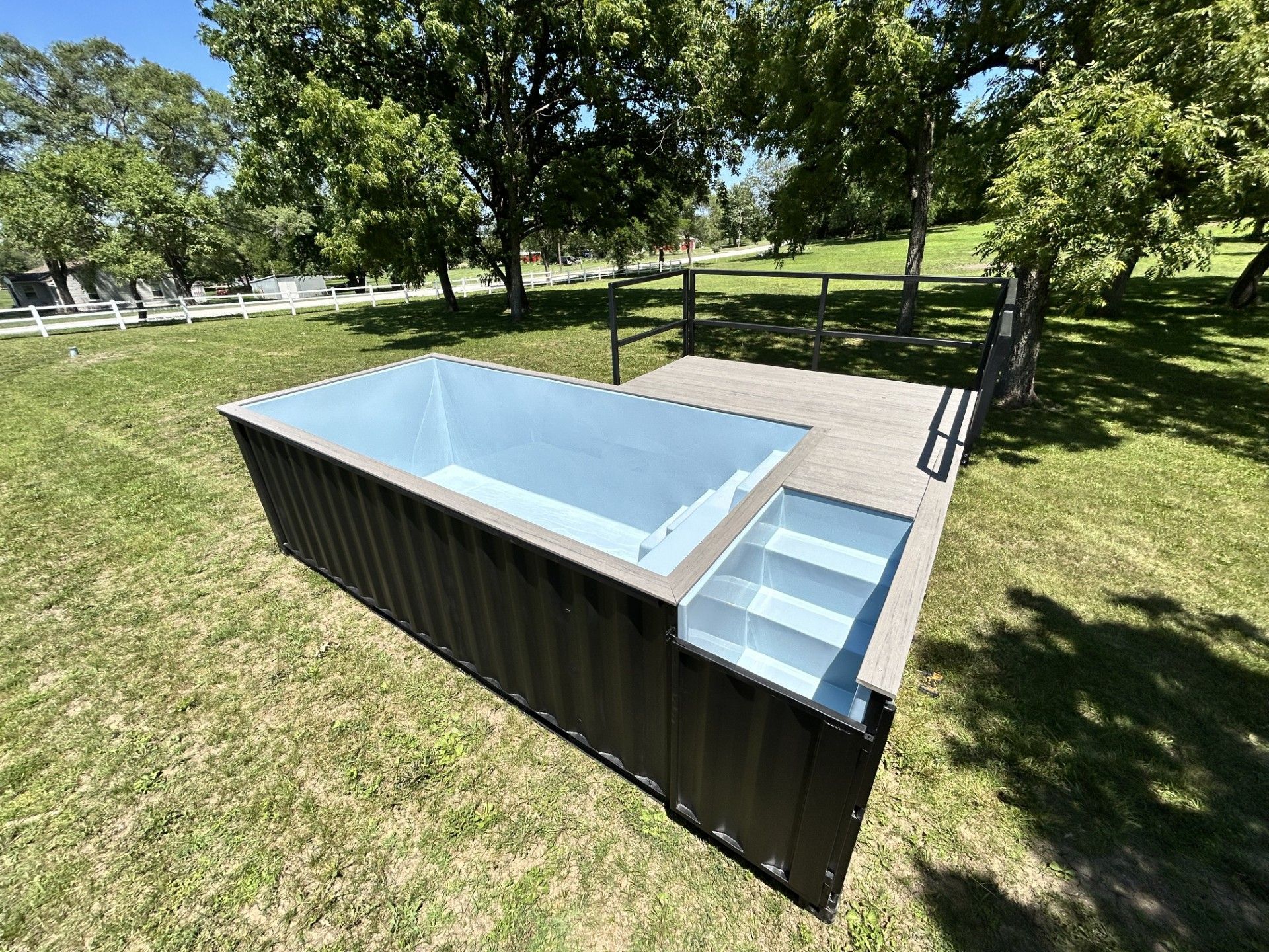 A large swimming pool is sitting on top of a lush green field.