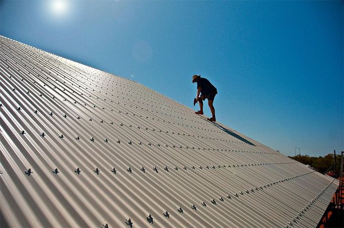 A Man Is Working On The Roof Of A Building