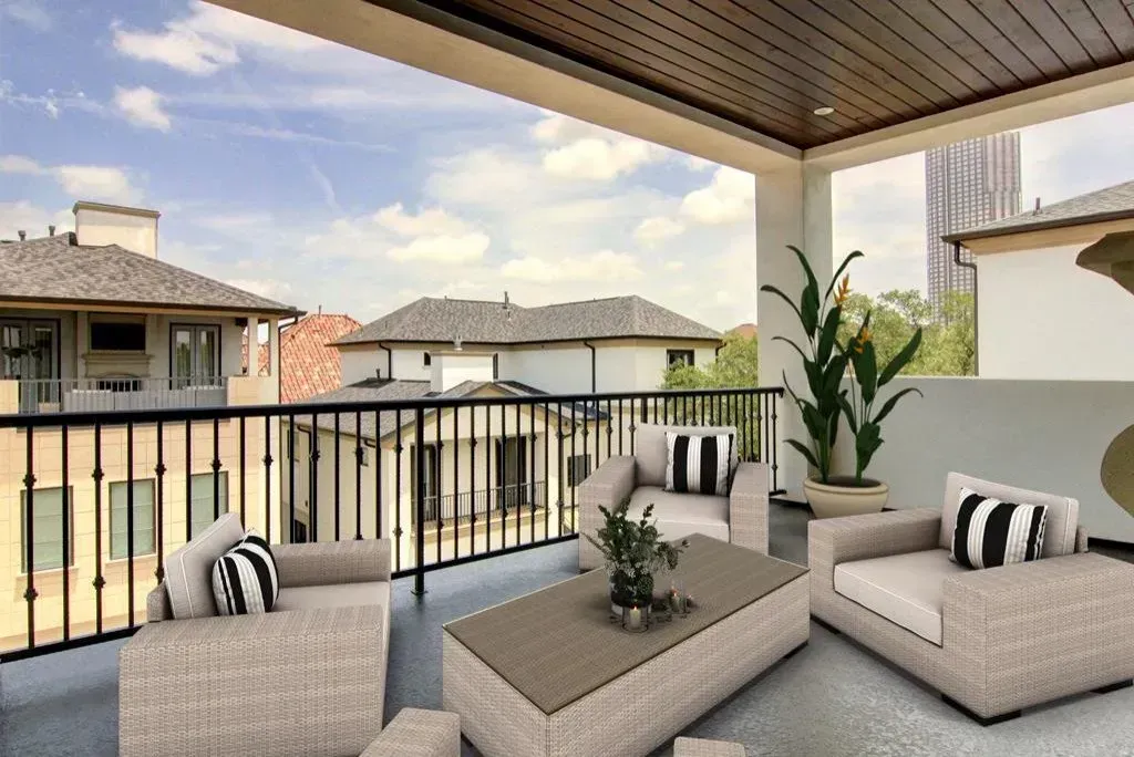 Outdoor patio with beige seating, black and white striped pillows, and a view of neighboring buildings.